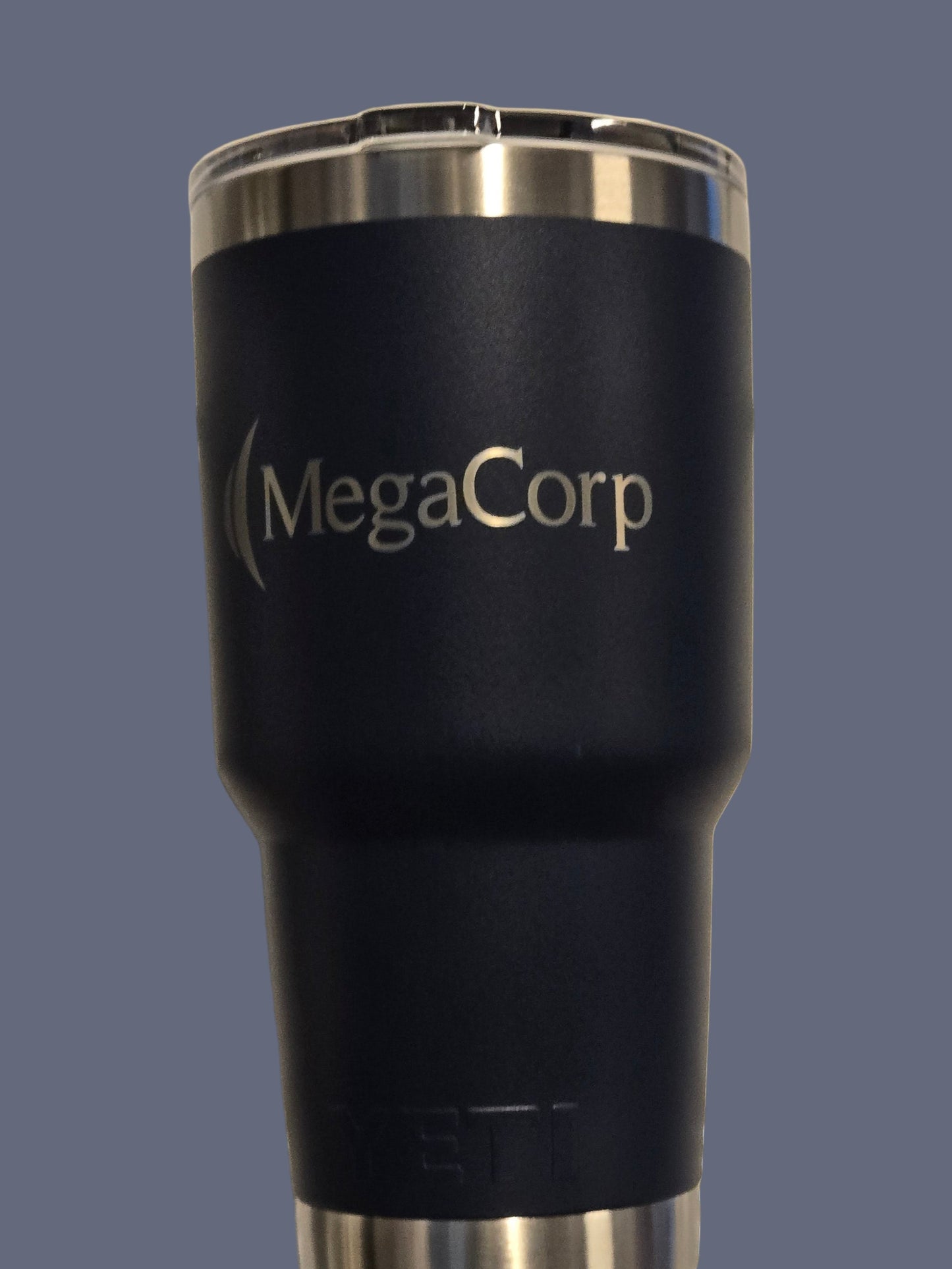 Black insulated tumbler with 'MegaCorp' branding on a metallic surface