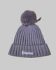Gray knit beanie with pom-pom on a wooden surface, featuring the MegaCorp logo.