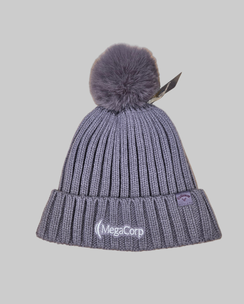 Gray knit beanie with pom-pom on a wooden surface, featuring the MegaCorp logo.