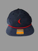 Navy blue cap with red brim and visible brand logo on a neutral background